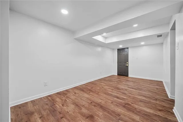 a view of an empty room with wooden floor and a closet