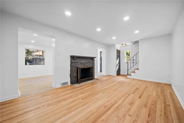 a view of an empty room with wooden floor and a fireplace
