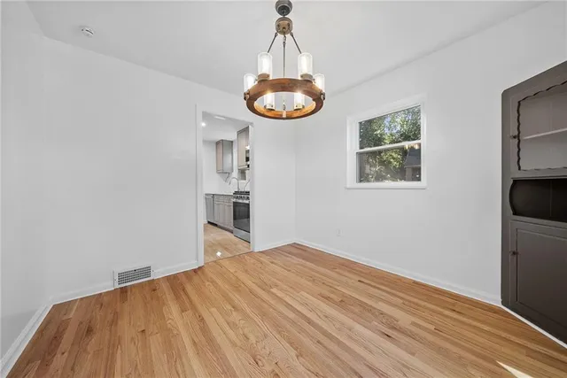 a big room with wooden floor a chandelier and closet