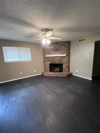 an empty room with windows fireplace and wooden floor