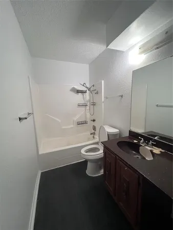 a bathroom with a granite countertop toilet a sink a mirror and bathtub