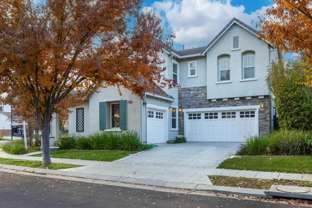a front view of a house with a garden and trees