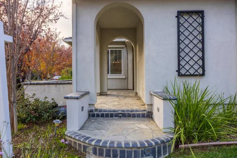 a view of a brick house with plants and wooden fence