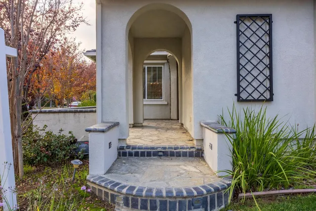 a view of a brick house with plants and wooden fence