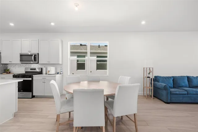 a view of a dining room with furniture wooden floor and a kitchen view