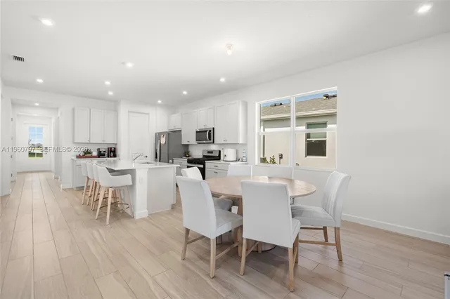 a kitchen with a refrigerator a stove a sink and chairs