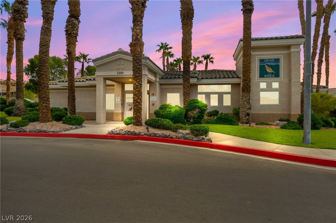 3376 Partridge Run Street Laughlin, NV 89029 - Photo 78 of 92 Palm trees frame the inviting community clubhouse entrance at sunset, offering a picturesque welcome.