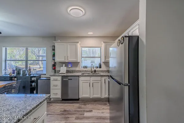 a kitchen with stainless steel appliances granite countertop a stove top oven a sink and dishwasher a refrigerator with wooden floor