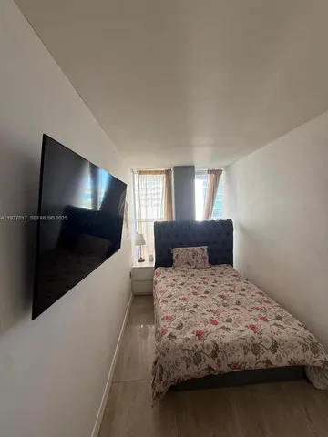 a bedroom with a large bed and a flat tv screen on dresser