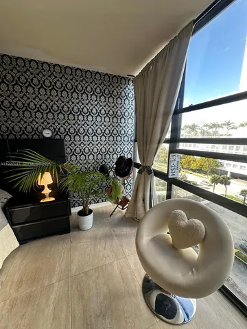 a living room with a chairs a rug and a floor to ceiling window