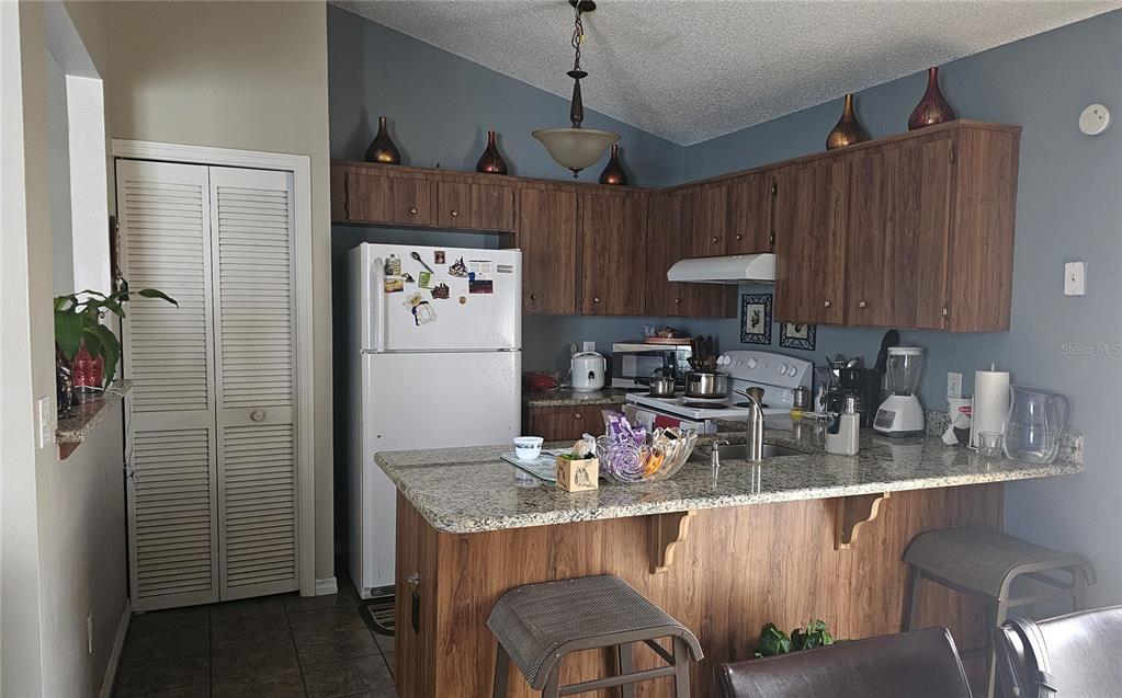 9906 Surrey Ridge Road Orlando, FL 32825 - Photo 5 of 18 a kitchen with stainless steel appliances granite countertop a refrigerator a stove a sink dishwasher and a dining table with wooden cabinet