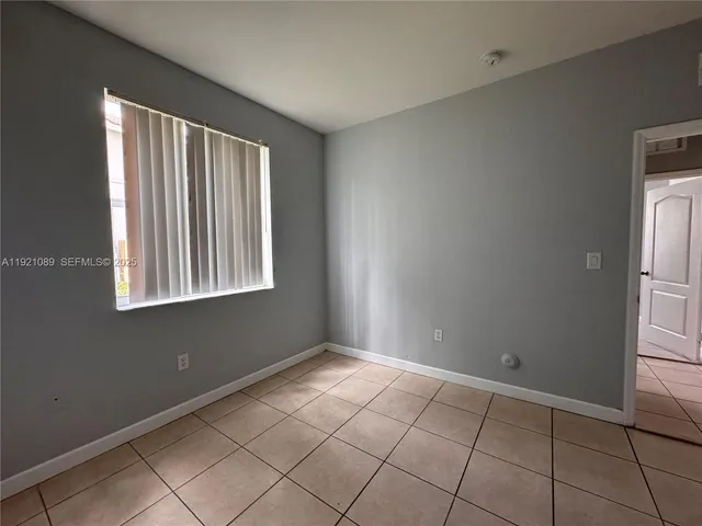 a view of an empty room with window and chandelier fan