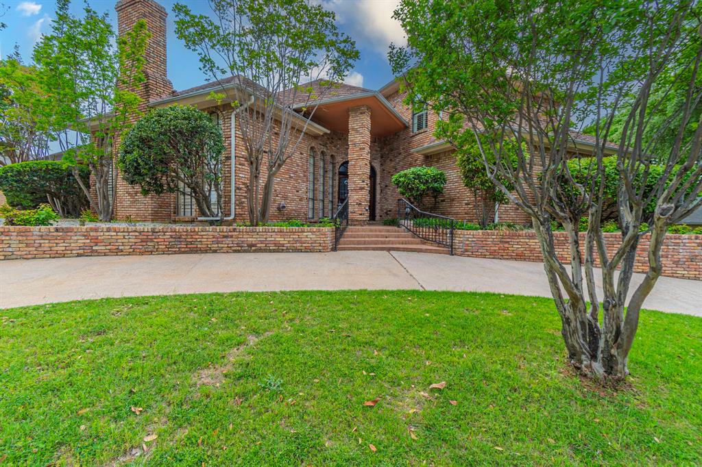 View of front facade featuring a front lawn, brick siding, and a chimney