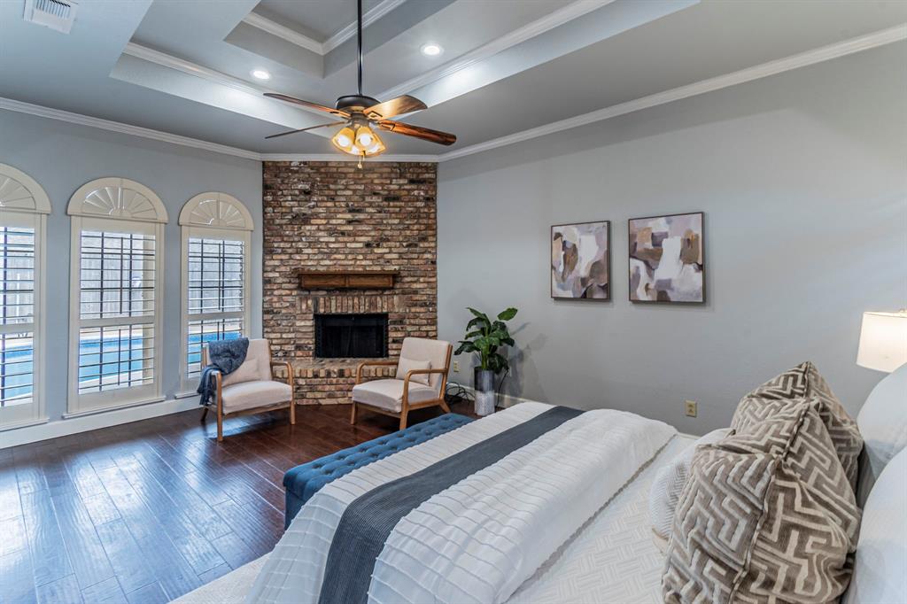 2714 Ridge Top Lane Arlington, TX 76006 - Photo 18 of 37 Bedroom with a brick fireplace, dark wood-style floors, crown molding, a tray ceiling, and ceiling fan