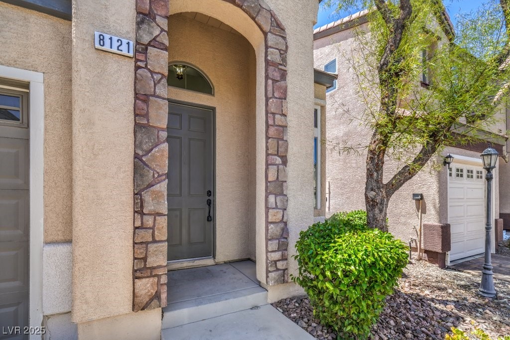 8121 Altamont Ridge Street Las Vegas, NV 89113 - Photo 4 of 27 View of exterior entry with stucco siding and ston