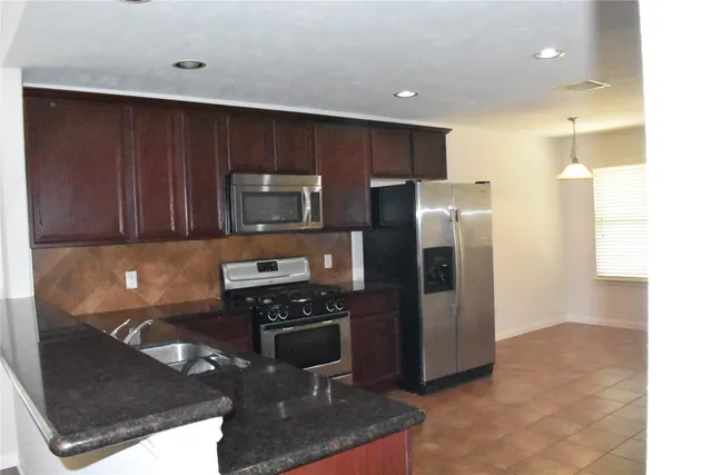 a kitchen with stainless steel appliances granite countertop a refrigerator and a stove top oven