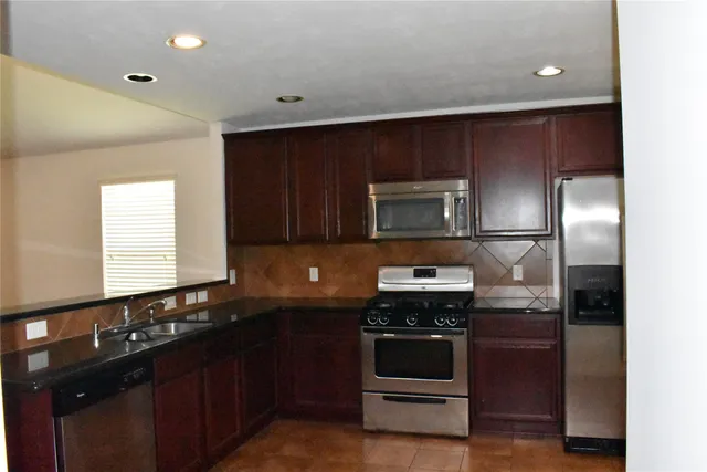 a kitchen with granite countertop stainless steel appliances and wooden cabinets