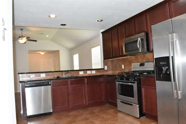 a kitchen with stainless steel appliances granite countertop a stove a microwave and a refrigerator