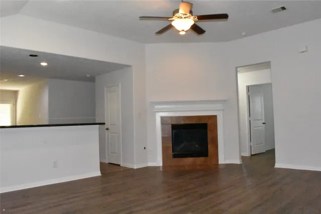 a view of an empty room with wooden floor and a fireplace