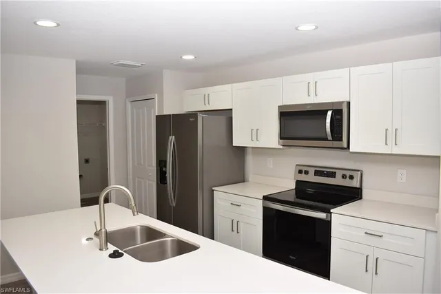 a kitchen with a sink a microwave a refrigerator and cabinets