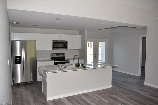 a kitchen with stainless steel appliances granite countertop a refrigerator a stove top oven a sink and dishwasher