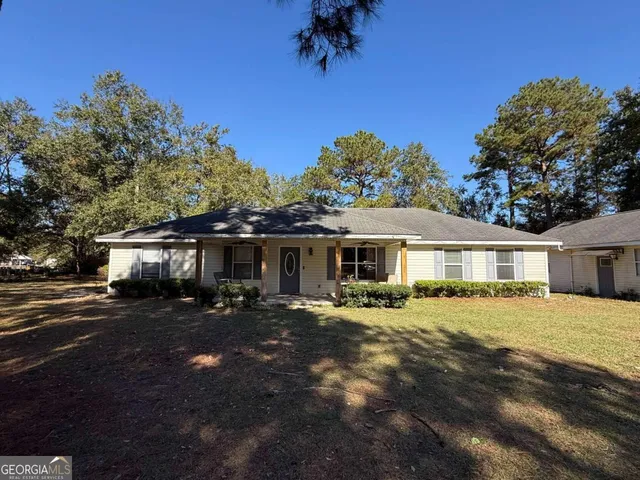 a front view of house with yard and trees in the background