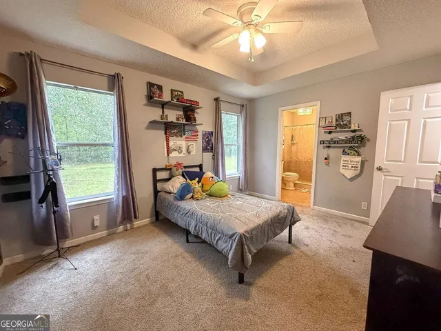 a spacious bedroom with a bed and a dresser next to a window