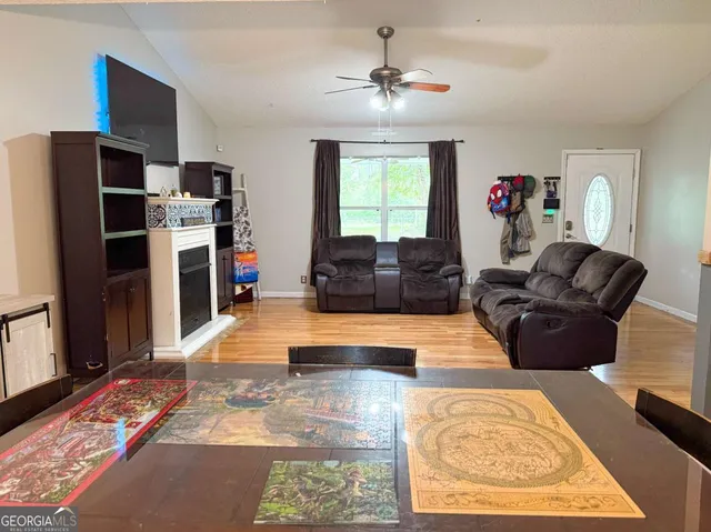 a living room with furniture a flat screen tv and a refrigerator