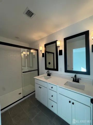 a bathroom with a double vanity sink mirror and bathtub