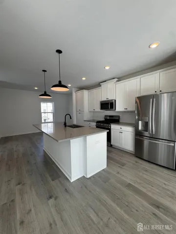 a kitchen with stainless steel appliances a stove a refrigerator and white cabinets