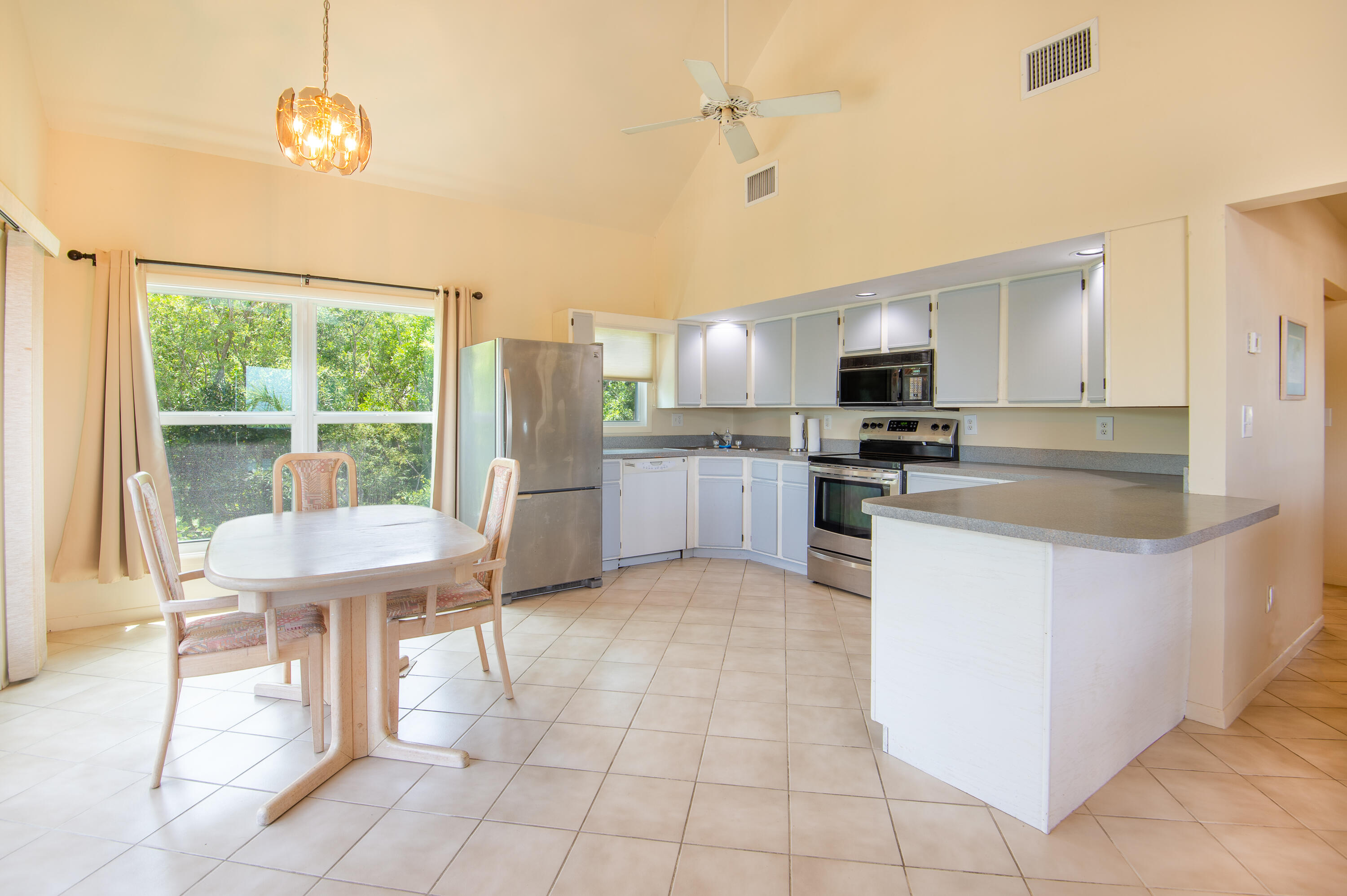 29015 Cedar Drive Big Pine Key, FL 33043 - Photo 9 of 38 a kitchen with stainless steel appliances granite countertop a stove top oven a sink a dining table and chairs