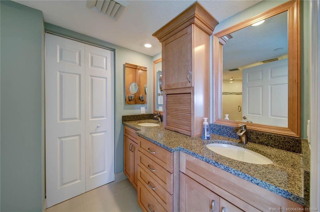 8800 South Ocean Drive, Unit 905 Jensen Beach, FL 34957 - Photo 28 of 67 a bathroom with a granite countertop sink and a mirror