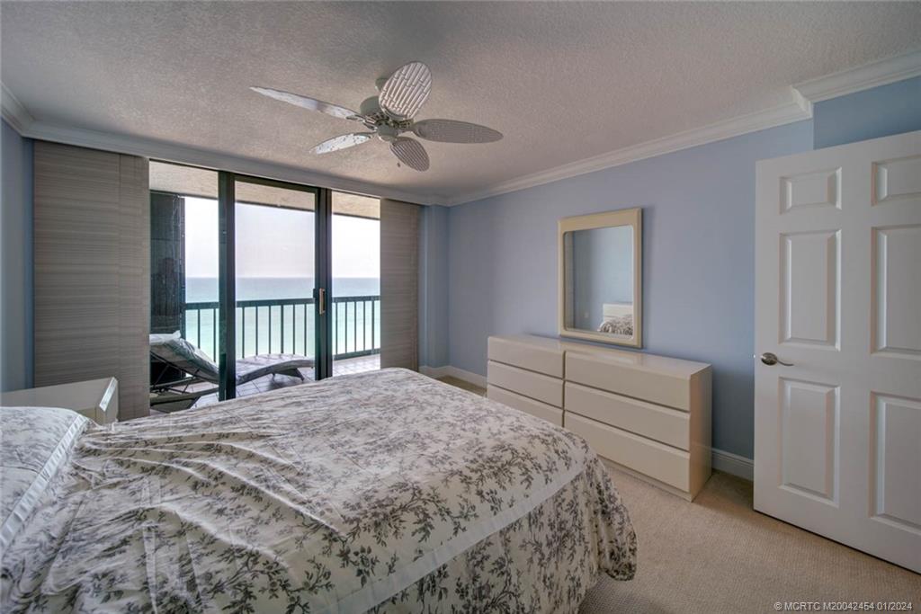 8800 South Ocean Drive, Unit 905 Jensen Beach, FL 34957 - Photo 30 of 67 a bedroom with a large bed and a chandelier fan