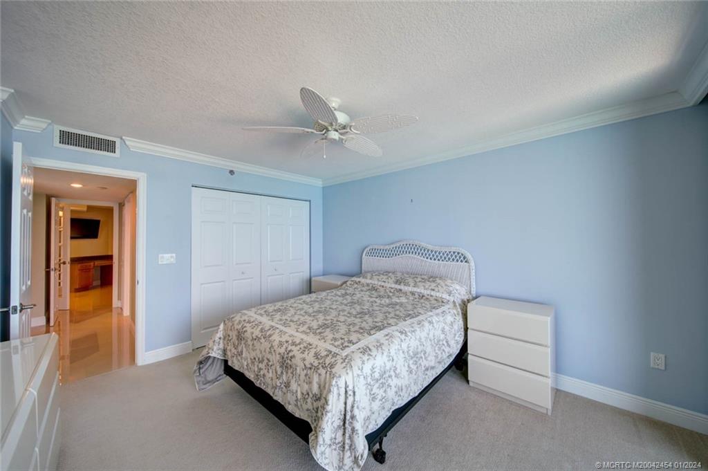 8800 South Ocean Drive, Unit 905 Jensen Beach, FL 34957 - Photo 32 of 67 a bedroom with a bed and a ceiling fan