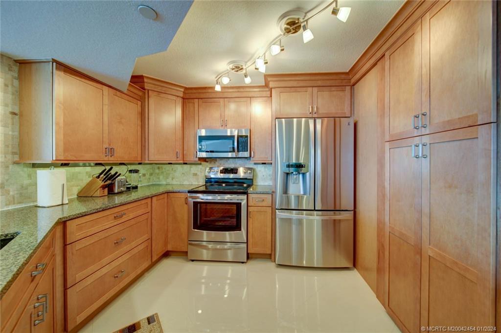8800 South Ocean Drive, Unit 905 Jensen Beach, FL 34957 - Photo 9 of 67 a kitchen with granite countertop stainless steel appliances a refrigerator a sink and cabinets