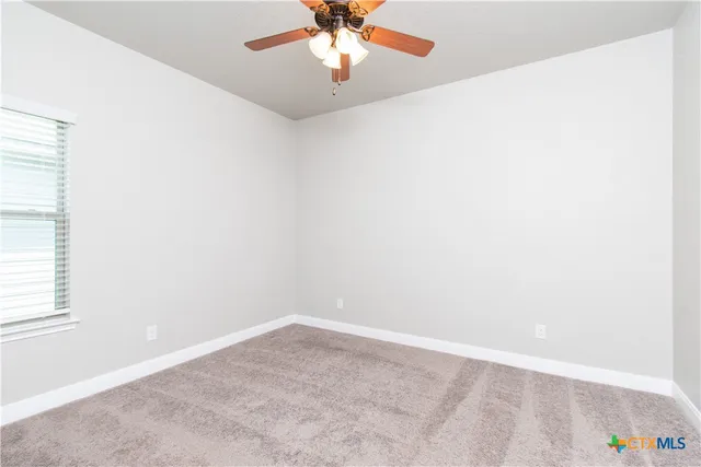 an empty room with a window and a ceiling fan