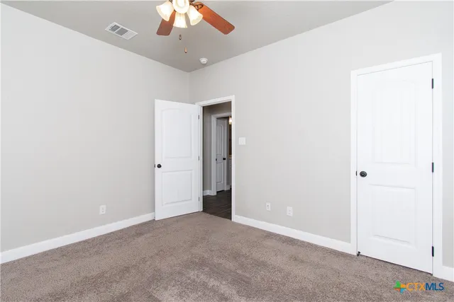 an empty room with a ceiling fan and a window
