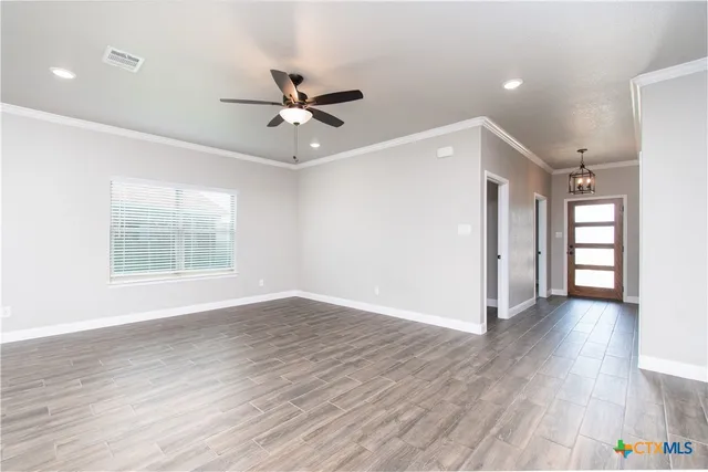 a view of an empty room with wooden floor and a window