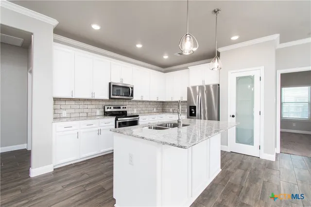 a kitchen with stainless steel appliances granite countertop a refrigerator a stove top oven a sink and dishwasher with wooden floor