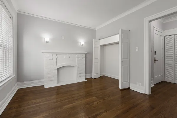 an empty room with wooden floor and fireplace