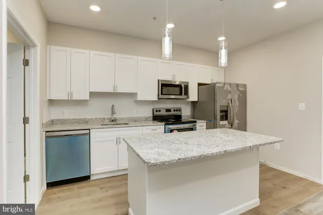 a kitchen with a sink a stove a refrigerator a center island and cabinets