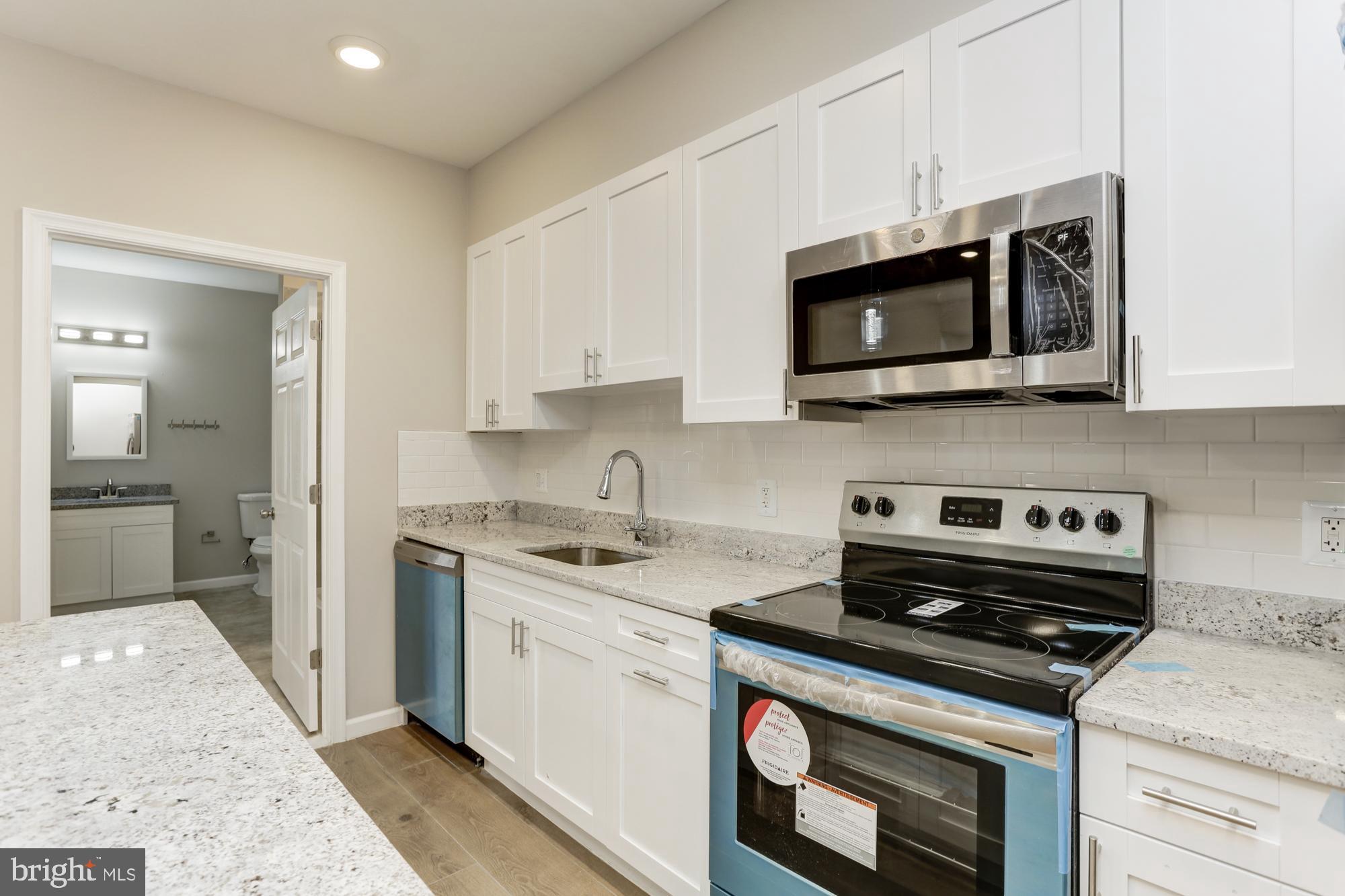 1923 Ashland Avenue, Unit 303 Baltimore, MD 21205 - Photo 6 of 13 a kitchen with stainless steel appliances a stove a microwave a sink and cabinets