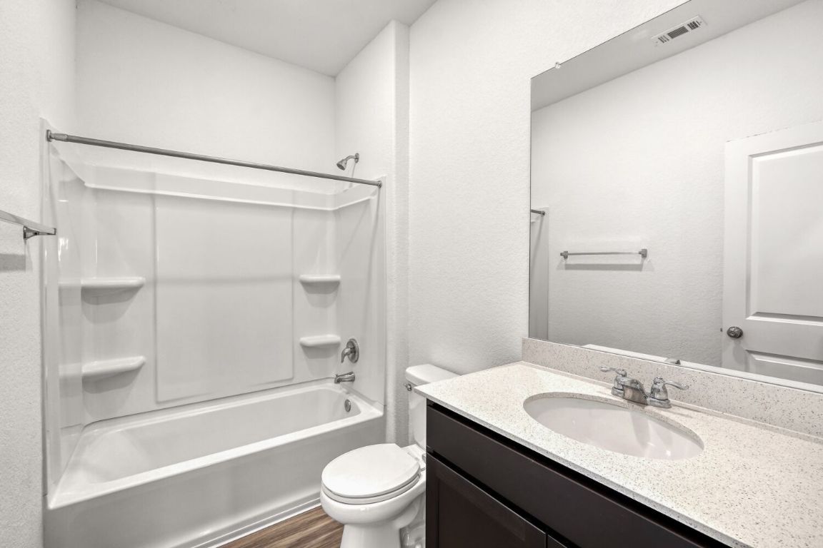 385 Geode Glen Maxwell, TX 78656 - Photo 15 of 16 Secondary bathroom featuring vanity, tub / shower combination, a textured wall, and dark wood finished floors