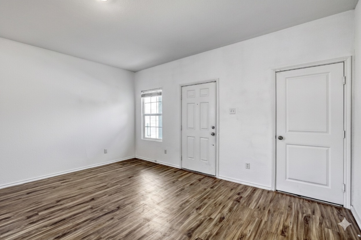 385 Geode Glen Maxwell, TX 78656 - Photo 4 of 16 Entrance to family room, front door and garage door featuring dark wood-style flooring and baseboards