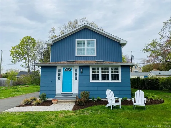 a brick house with a yard potted plants and a table and chair