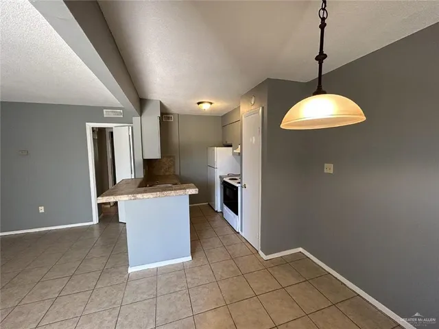 a kitchen with kitchen island a counter top space appliances and a chandelier