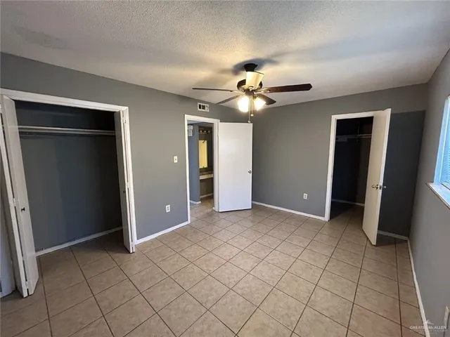 an empty room with closet and a chandelier fan
