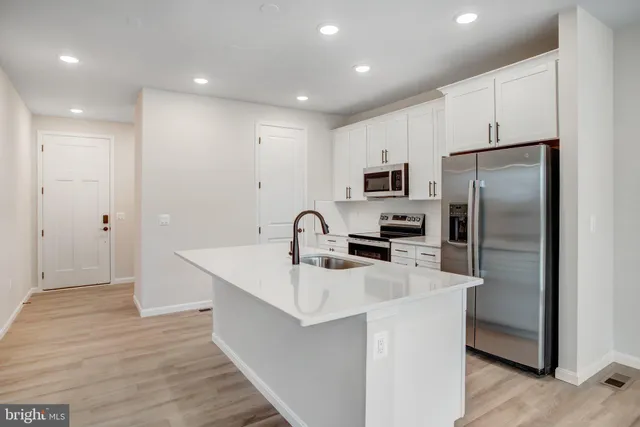 a kitchen with kitchen island a sink stainless steel appliances and refrigerator