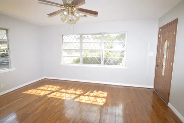 a view of an empty room with wooden floor and a window