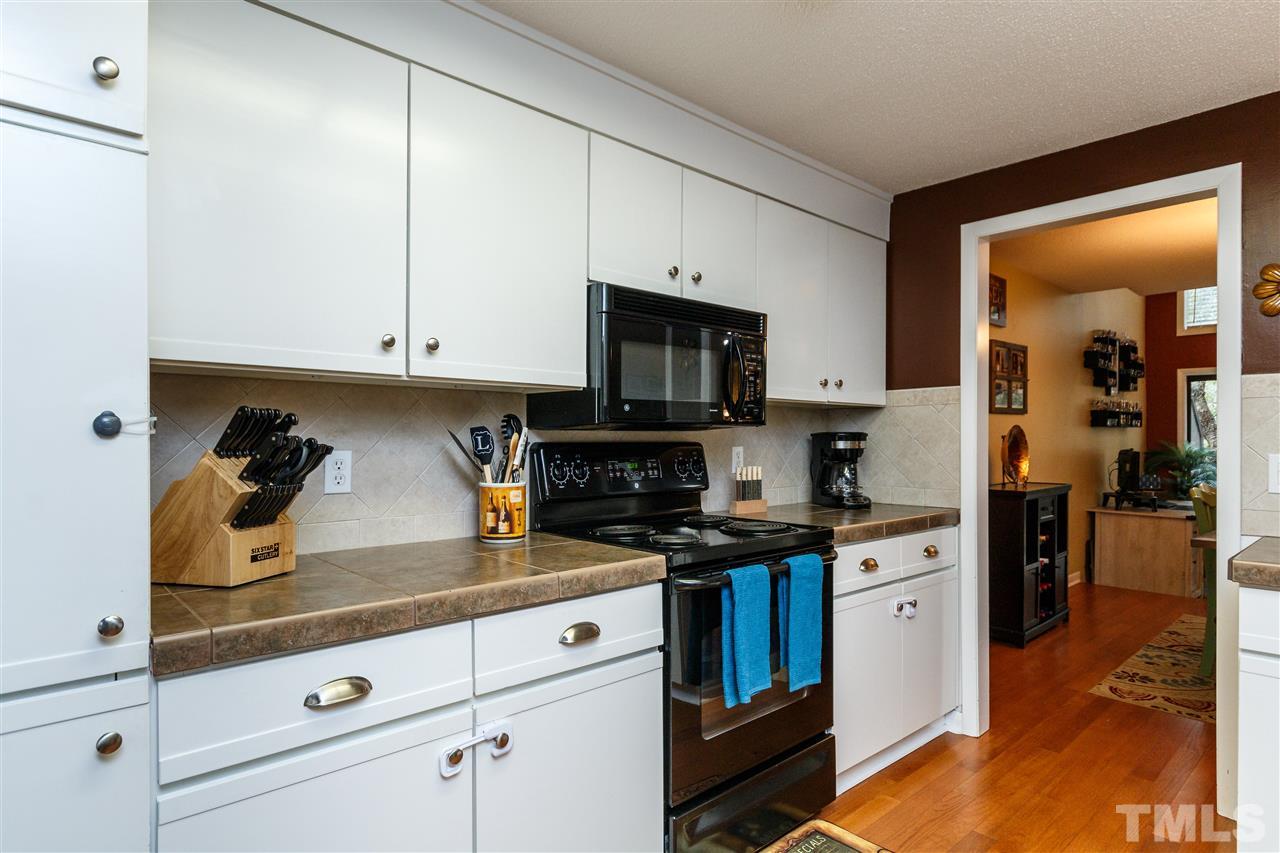 4411 Sunscape Lane Raleigh, NC 27613 - Photo 7 of 25 a kitchen with white cabinets and appliances